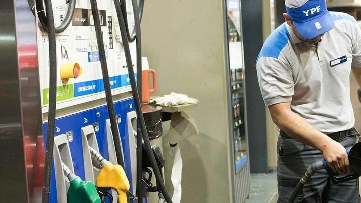 Playero de YPF despacha combustible en el surtidor de una estación de servicio
