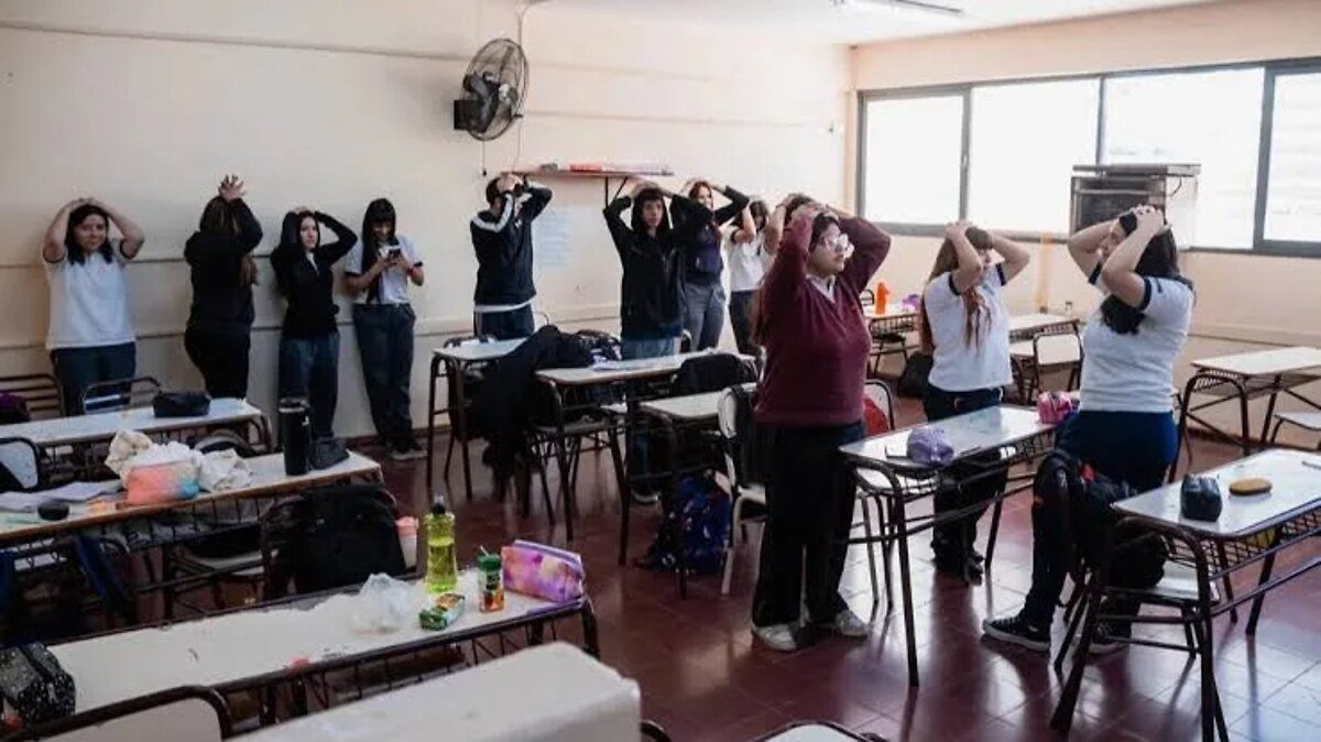 Estudiantes en aula durante un simulacro de sismo, con las manos sobre la cabeza