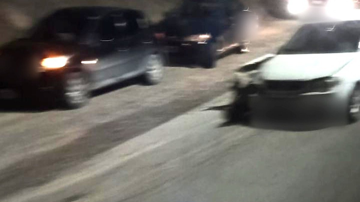 Auto blanco con el frente dañado sobre la Ruta 153, de noche, con otros vehículos y un camión con luces encendidas detrás