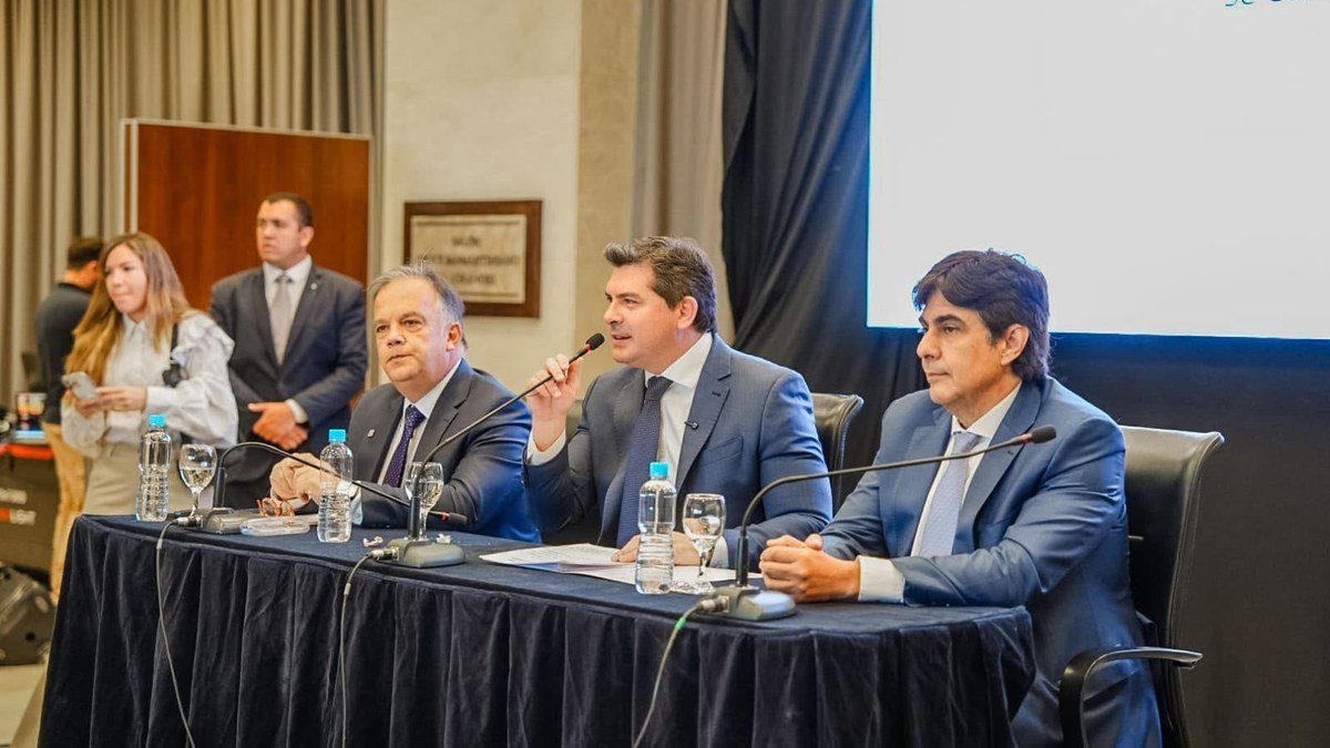 Marcelo Orrego habla con un micrófono en una mesa de presentación, junto a dos funcionarios