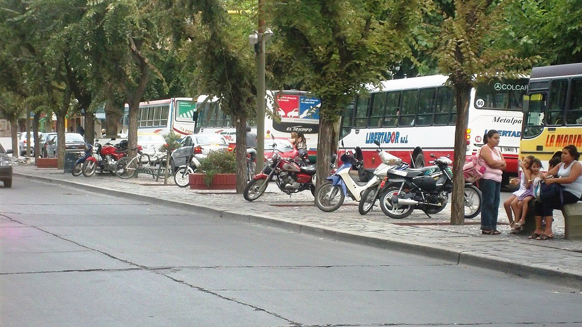 Avenida Libertador San Martín en el centro de San Juan, con árboles, motos estacionadas y colectivos