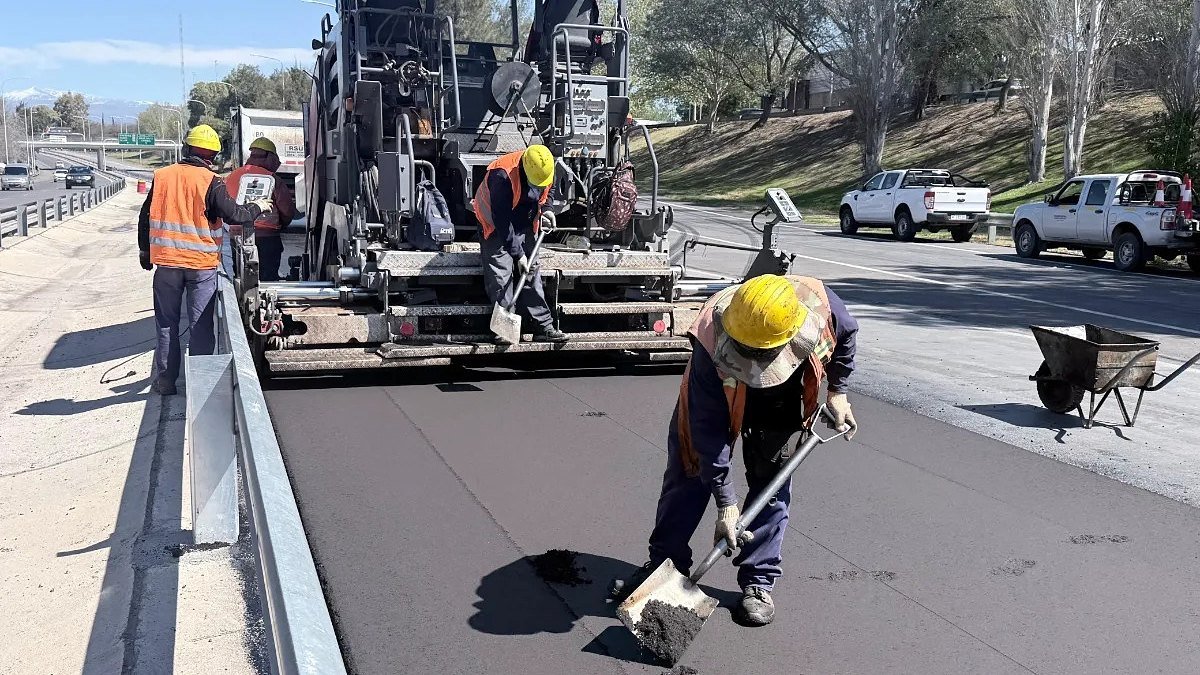 Operarios con casco trabajan junto a una terminadora de asfalto en la avenida de Circunvalación