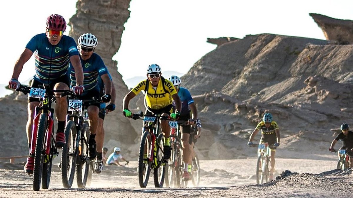 Ciclistas de mountain bike pedalean por un camino de ripio entre formaciones rocosas de Ischigualasto