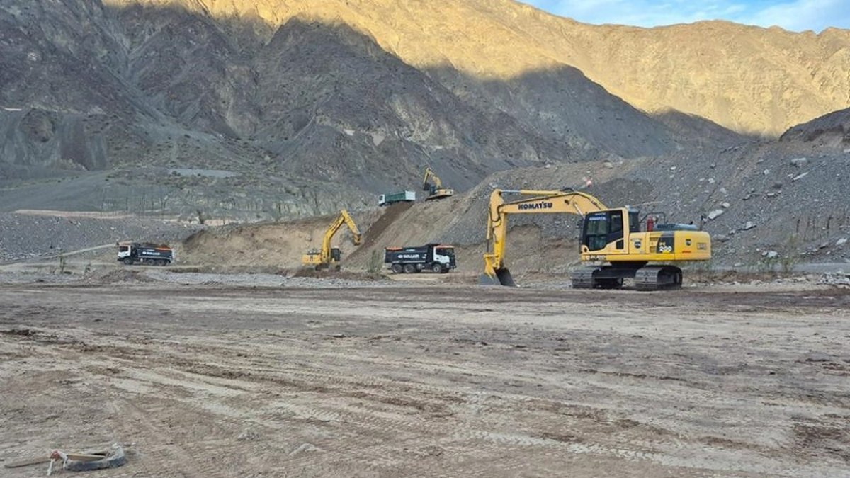 Excavadoras y camiones trabajan sobre el lecho del río San Juan, al pie de los cerros