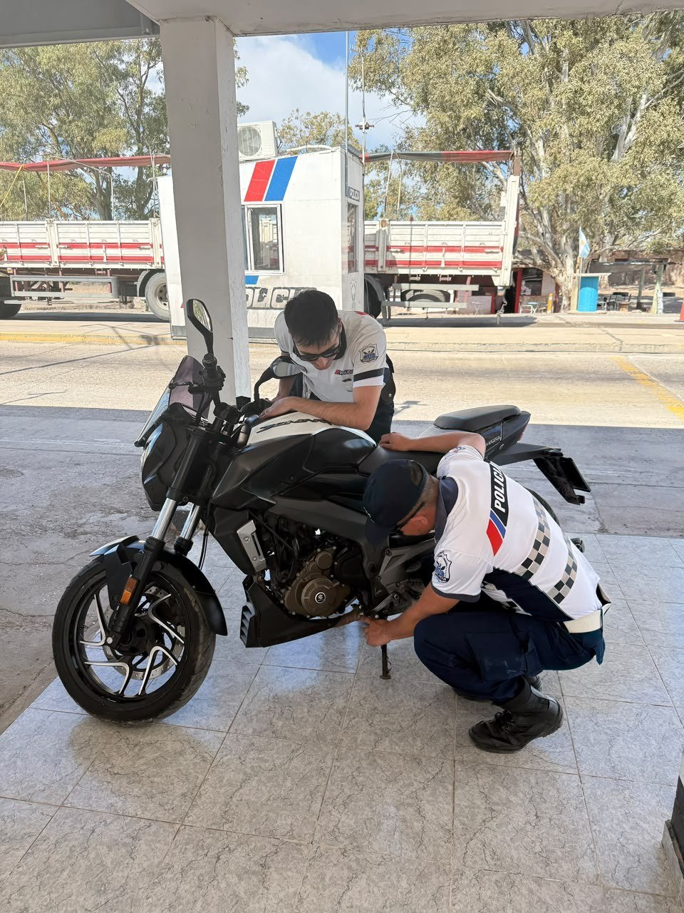 Dos efectivos revisan una motocicleta Bajaj bajo la galería del puesto policial San Carlos, en Sarmiento.