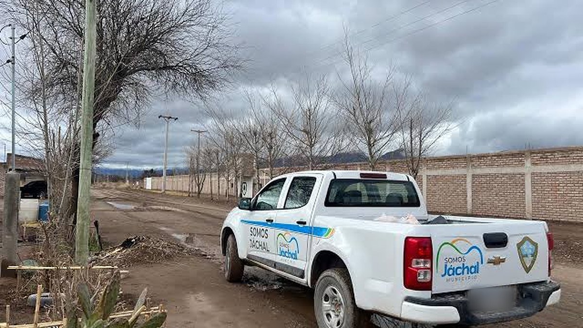 Camioneta blanca del Municipio de Jáchal estacionada en una calle de tierra embarrada, con cielo nublado