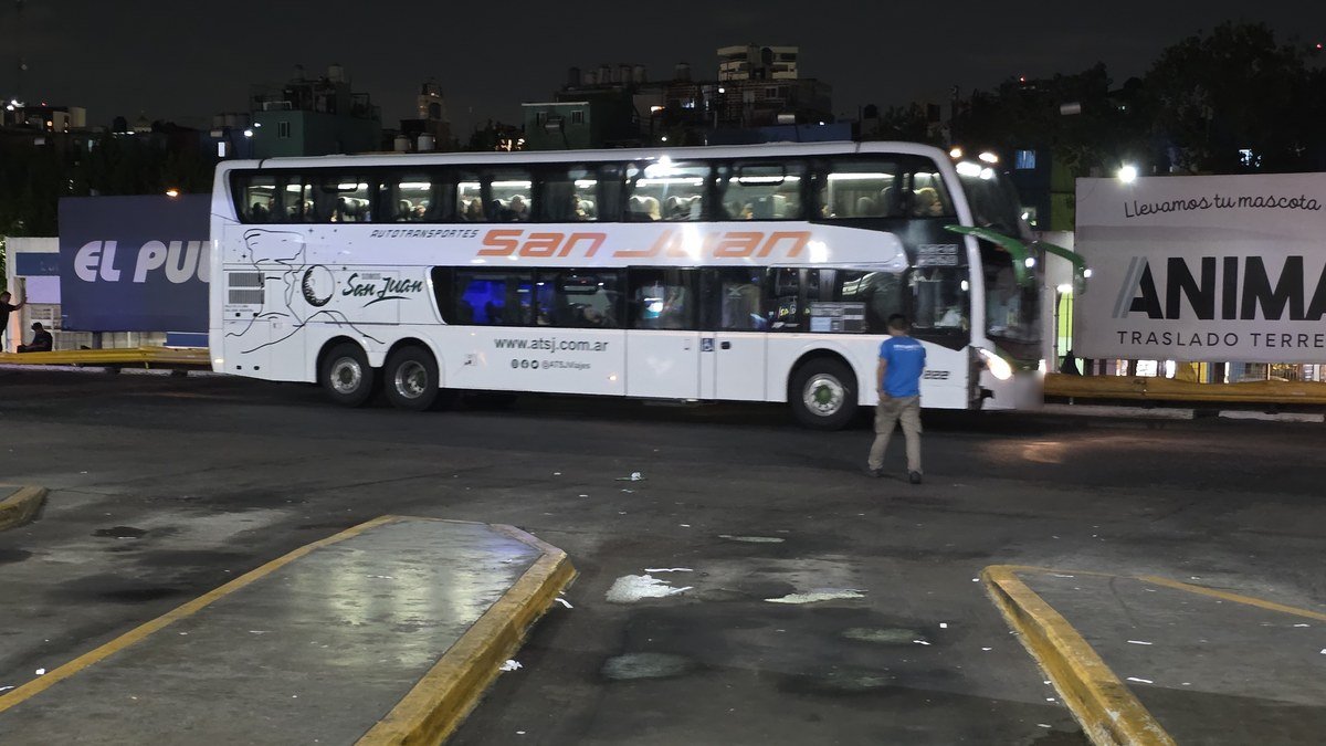 Colectivo de larga distancia de Autotransportes San Juan estacionado en una terminal de noche