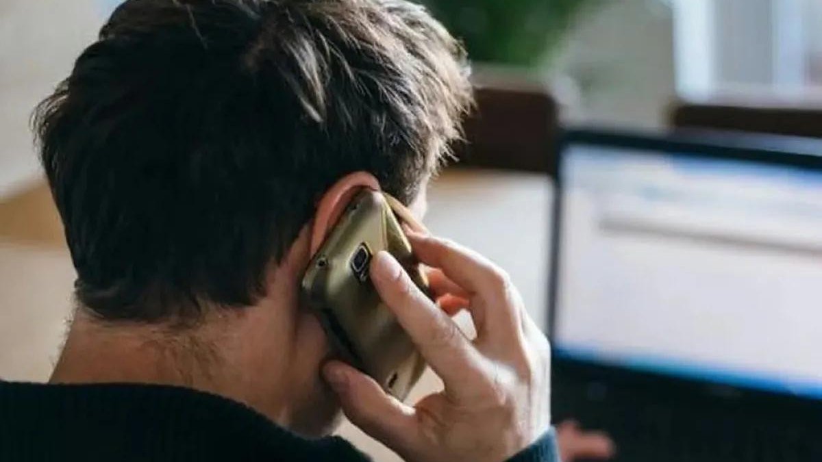 Un hombre habla por teléfono celular frente a una computadora