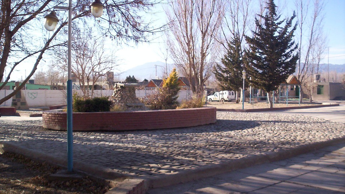 Plaza de Rodeo, en Iglesia, con árboles sin hojas, faroles y montañas al fondo