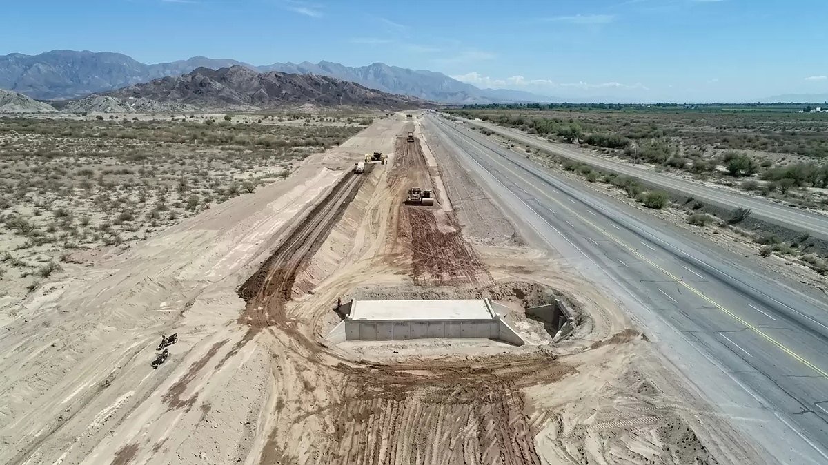 Vista aérea de trabajos de movimiento de suelo junto a la Ruta 40, con montañas al fondo