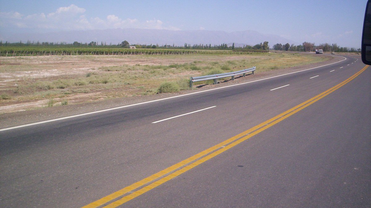 Ruta de dos carriles con doble línea amarilla atravesando una zona rural de San Juan
