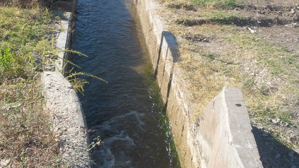 Canal de riego de hormigón con agua en una zona rural de Tres Esquinas, Sarmiento
