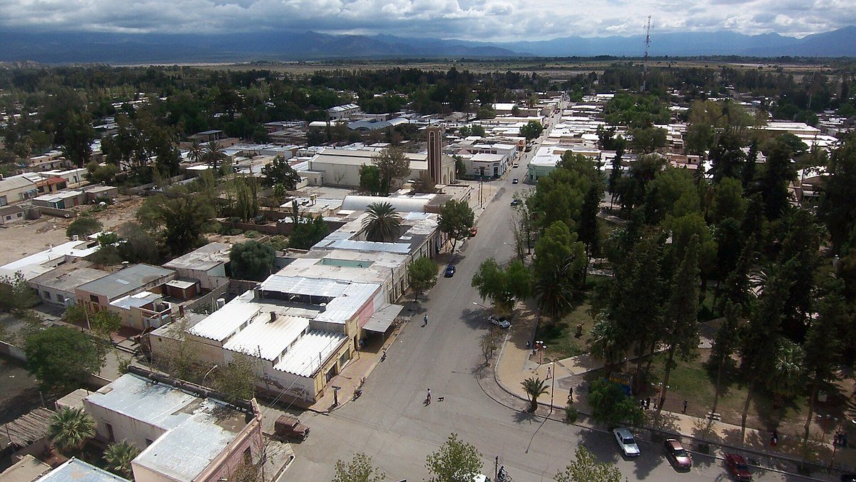 Vista aérea de casas y calles arboladas de una ciudad sanjuanina, con la montaña al fondo