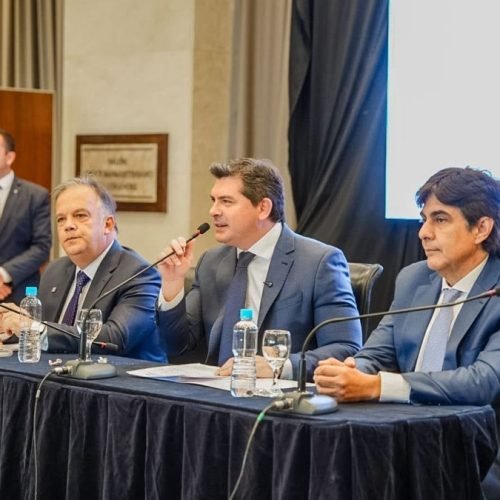 Marcelo Orrego habla con un micrófono en una mesa de presentación, junto a dos funcionarios