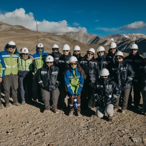 Un grupo de personas con cascos y ropa de trabajo posa en un sector de montaña del proyecto Vicuña