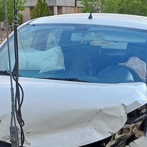 Auto blanco con el frente destrozado y las bolsas de aire desplegadas, junto a un poste de madera en una vereda de Media Agua