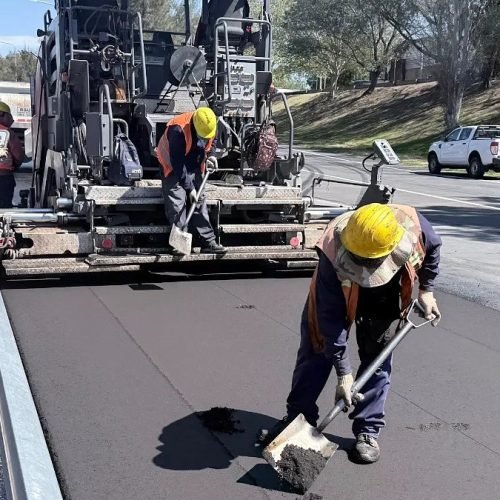 Operarios con casco trabajan junto a una terminadora de asfalto en la avenida de Circunvalación