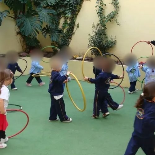 Clase de educación física con aros en un patio