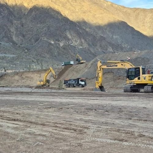 Excavadoras y camiones trabajan sobre el lecho del río San Juan, al pie de los cerros