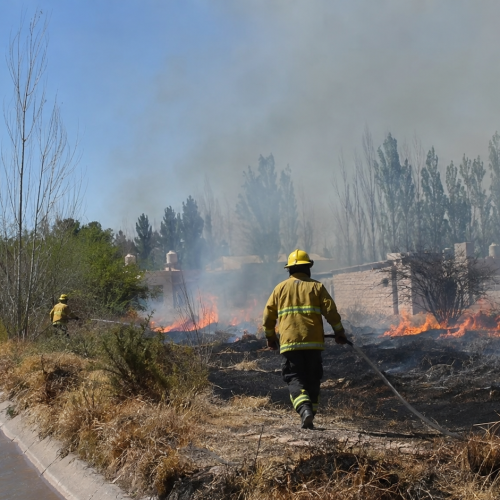 Bomberos combaten un incendio junto a un canal de Sarmiento, imagen ilustrativa generada con IA.