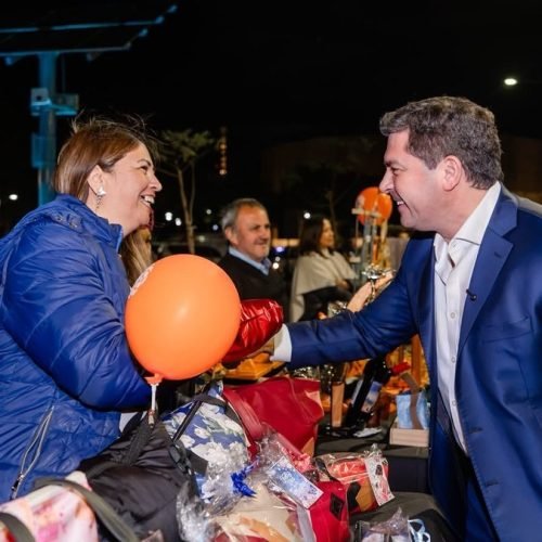 El gobernador Marcelo Orrego saluda a una emprendedora en un puesto de la Expo Mamá, de noche, en el Parque Belgrano