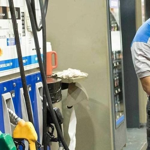 Playero de YPF despacha combustible en el surtidor de una estación de servicio