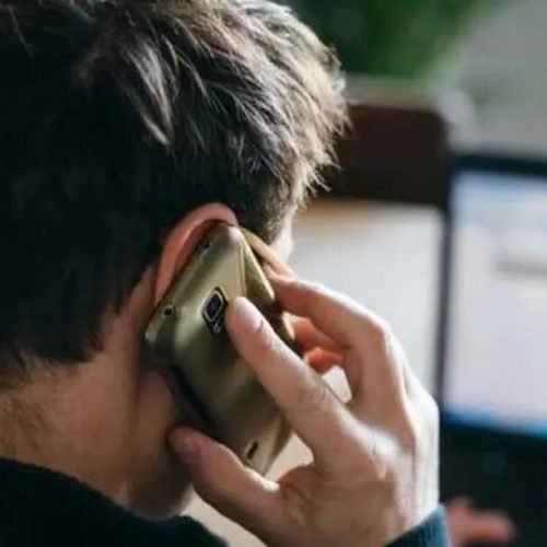 Un hombre habla por teléfono celular frente a una computadora