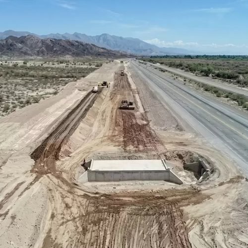 Vista aérea de trabajos de movimiento de suelo junto a la Ruta 40, con montañas al fondo