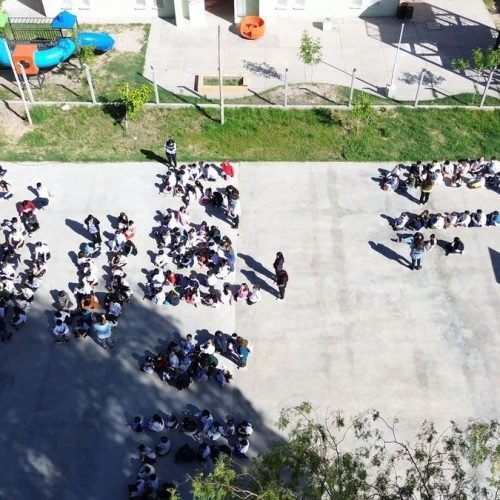 Vista aérea de estudiantes agrupados en el patio de una escuela de San Juan durante un ensayo de evacuación por sismo